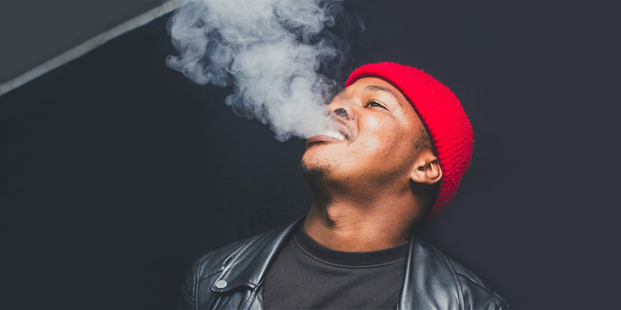 a black man wearing red beanie and a black leather jacket while vaping